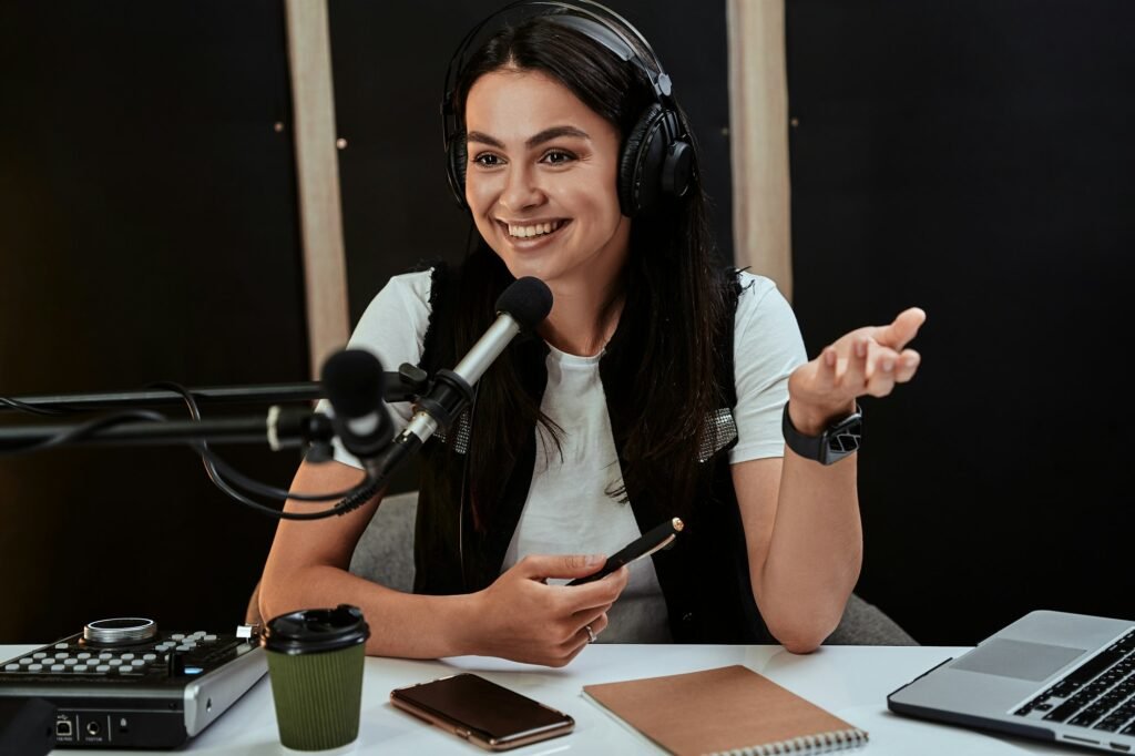 Portait of attractive young female radio host looking emotional while speaking in microphone